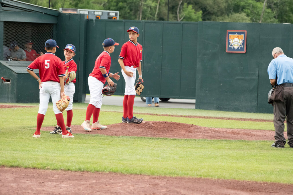 Youth baseball infielders gather around the pitcher to show support at Cooperstown Dreams Park.