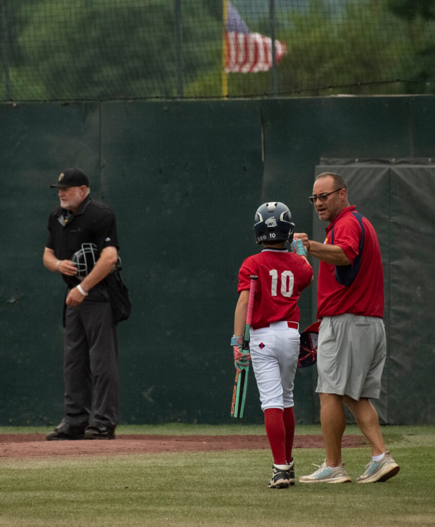 Youth baseball coach sharing a one-on-one moment with a player at Cooperstown Dreams Park.
