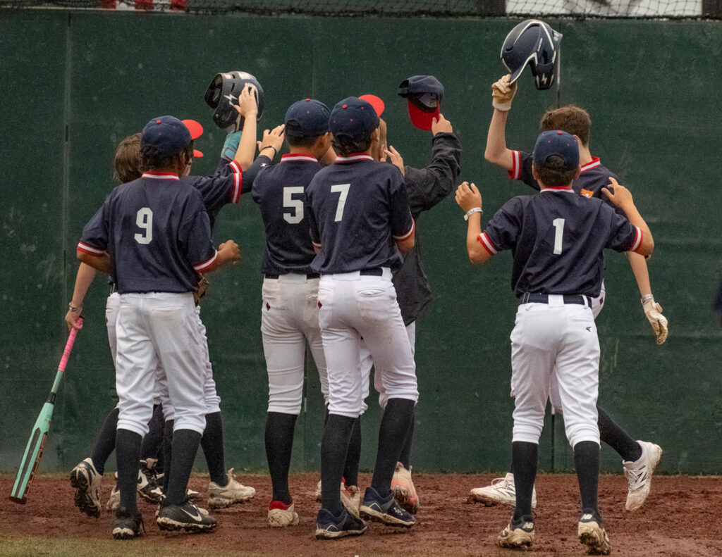 Youth baseball team gathering around a player after he hits a home run at Cooperstown Dreams Park.
